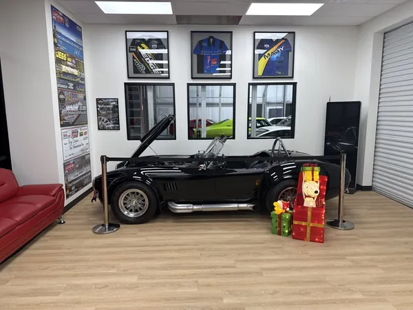 Customer lounge with a Shelby Cobra, framed jerseys and a red sofa