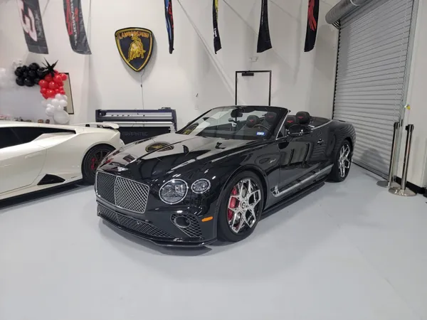 Black Bentley convertible in the showroom with balloons