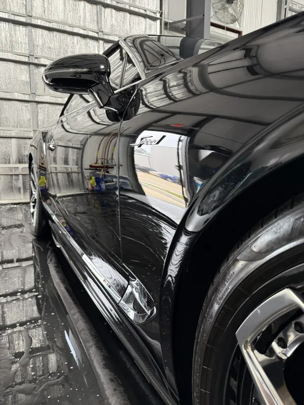 Deep reflections along a black car's flank