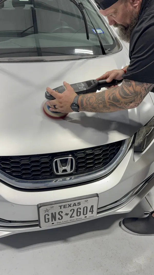 Tech polishing a white Honda hood