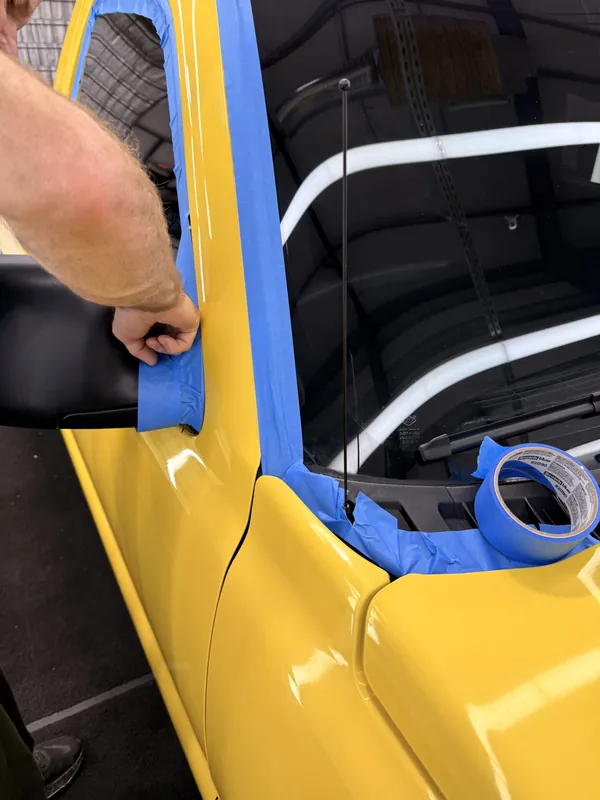 Masking a yellow car's door edge before polishing