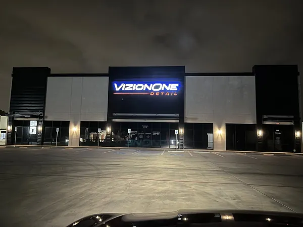 VizionOne Detail storefront at night with the sign lit