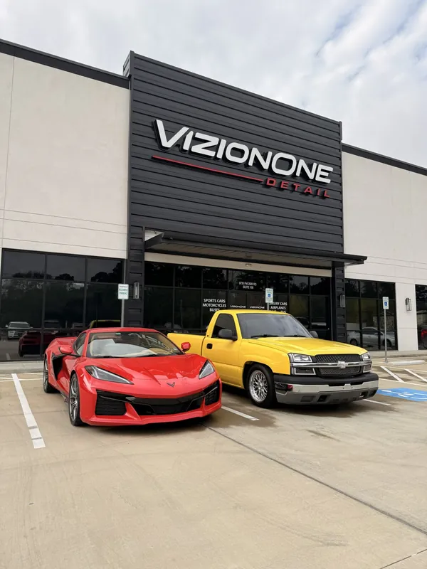 Red Corvette and a yellow Chevy truck outside the shop