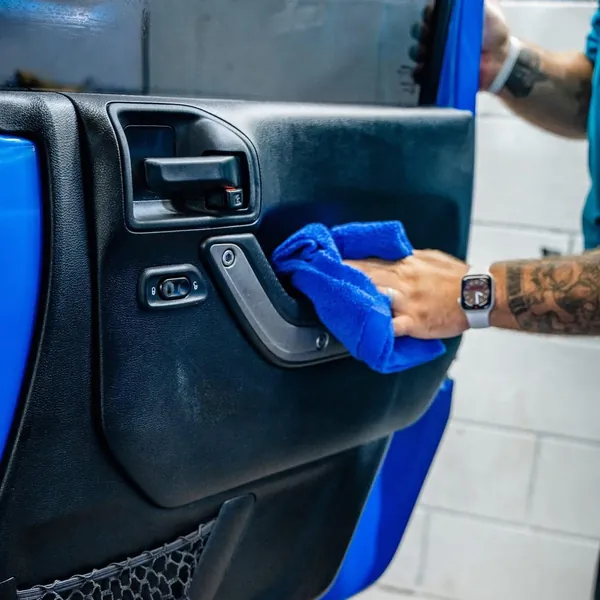 Tech wiping a blue Jeep door panel