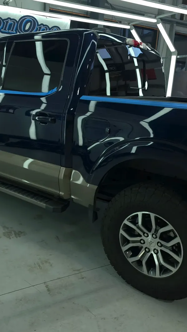 Blue Ford F-150 taped off under the light tunnel