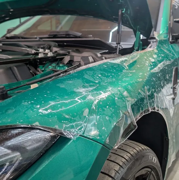 Wet paint protection film being laid on a green car