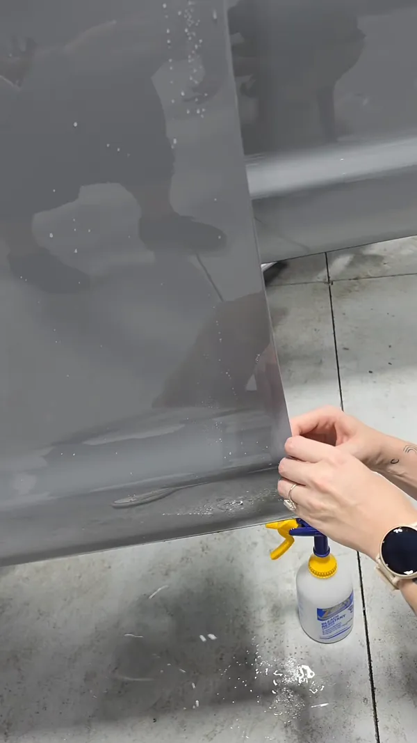 Installer laying paint protection film on a white truck door