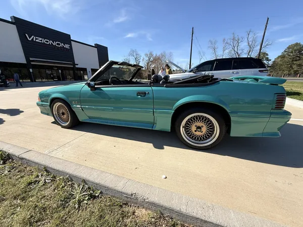 Teal Fox-body Mustang convertible outside the shop