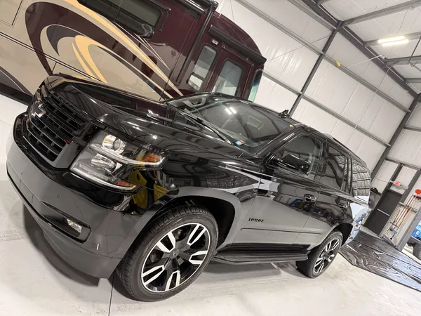 Black Chevy Tahoe in the bay with a motorhome behind it