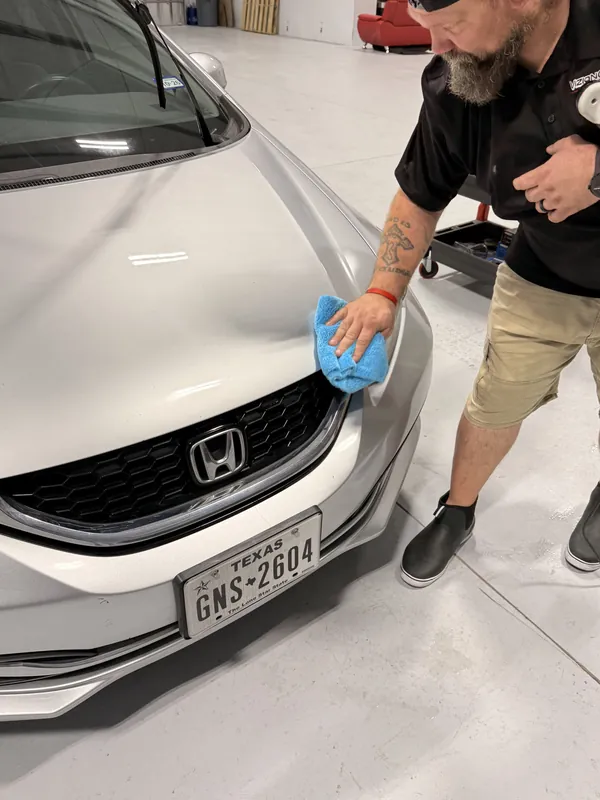 Tech wiping down a white Honda hood